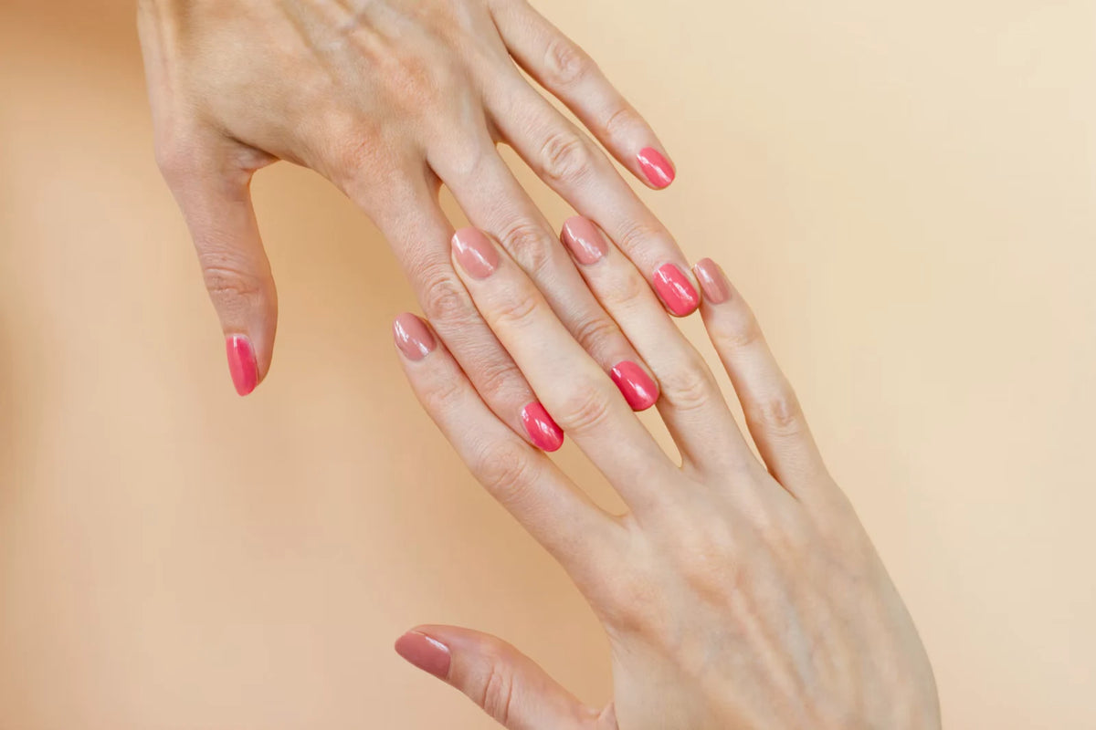 Glossy pink and nude manicures against a warm beige background