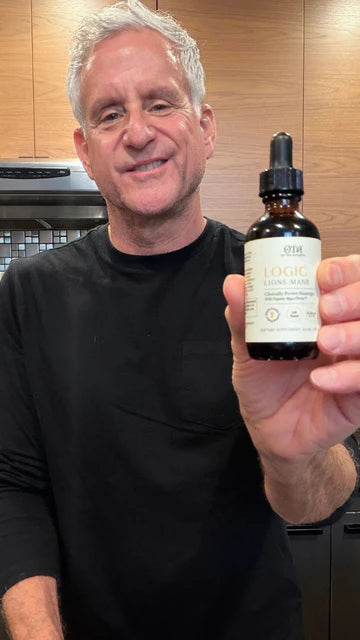 Man holding a bottle of Logic Lion's Mane supplement indoors.