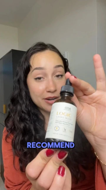 Woman holding a bottle of Logic Lion's Mane with a blurred indoor background